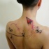 Sweet looking colored upper back tattoo of paper plane with butterflies