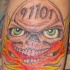 el tatuaje 911 de una calavera con ojos verdes y el fuego en su boca