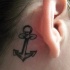 Piccola ancora femminile tatuata vicino l'orecchio