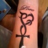 Croix avec le coeur le tatouage sur le bras