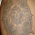 Tatuaje en el hombro de un calendario de muerte de estilo azteca.