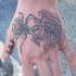 Tatuaje en tinta negra araña con teleraña en la mano