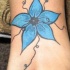 Le tatouage d'une jolie fleur bleu