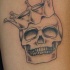 cranio in corona inchiostro nero tatuaggio
