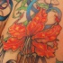 el tatuaje de una flor de lirio con una mariposa u otros detalles hecho en color
