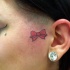 Tatuaje en la cara, pequeño lazo rojo