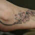 Ramo con fiori tatuato sul piede