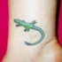 El tatuaje chicho de una lagartija de color verde en la pierna