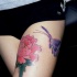 tatuaje en la cadera de mariposa morada y flor rosa