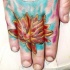 Tatuaje en la mano, lirio rojo en el agua