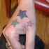Tatuaje en la mano, tres estrellas de colores diferentes