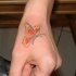 Tatuaje en la mano, mariposa bonita, de colores rojo, amarillo