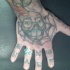La faccia che sorride, la ragnatela tatuati sulla mano e segni tatuati sulle dita