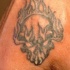 Tatuaggio non colorato sulla mano il teschio nelle fiamme