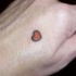 Tatuaje en la mano, corazón rojo con contornos negros, diseño muy diminuto