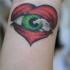 Le tatouage de cœur avec un œil vert sur le poignet
