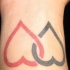 tatuaje en la muñeca de corazones en rojo y negro