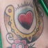 Tatuaje multicolor de una herradura con corazon dentro