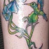 Tatuaje multicolor de un colibrí y las flores