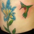 tatuaje de colibrí verde en flor azul