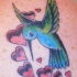 Le tatouage d'un joli colibri et des coeurs