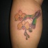 el tatuaje colorado de dos orquideas con un colibri
