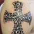 Negro tatuaje en hombro con cruz con tracería