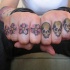 Quatre fleurs rouges avec le tatouage de crânes sur les phalanges