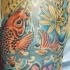 El tatuaje de un pez koi y una flor de loto hecho en color en el brazo o hombro