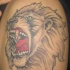 El tatuaje de la cabeza de un leon rugiendo con ojos de color