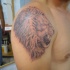 El tatuaje de la cabeza de un leon rugiendo realista detallado en el hombro