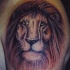 El tatuaje de la cabeza de un leon triste en el hombro