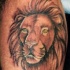 El tatuaje de la cabeza de un león con ojos de color en la pierna