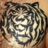 El tatuaje tribal de la cabeza de un tigre en negro hecho en el pecho