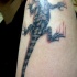 El tatuaje realista de una lagartija rascando la piel en el brazo o hombro