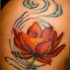 el tatuaje de una flor de loto de color naranja en el viento