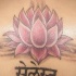 el tatuaje de una flor de loto de color rosa con el escrito en hindu hecho en la espalda
