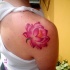 el tatuaje de una flor de loto acuarela hecho en el hombro