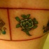 el tatuaje en color de una flor de loto y unos simbolos en forma de brazalete