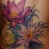 el tatuaje muy tierno de tres flores de loto de color  morado y verde hecho en la espalda