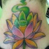 el tatuaje de una flor de loto con humo de color verde hecho en el cuello
