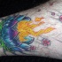 el tatuaje de muchos colores de una flor de loto con fuego hecho en la pierna