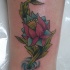 el tatuaje de una flor de loto con tallo en el  agua hecho en color en la pierna