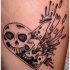 el tatauje de las calaveras dentro de una corazon roto hecho en color negro