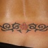 Tatuaje en el bajo de la espalda, pequeña flor con tracería negra
