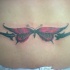 Muy enigmática mariposa en colores negro y rojo tatuaje en bajo de espalda