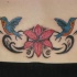 tatuaje en el bajo de la espalda de flor y colibrís