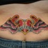 Tatuaje en el bajo de la espalda, corazón, decoración de alas en color