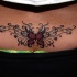 Mariposa en rojo con tracería, tatuaje en el bajo de la espalda