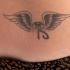 Tatuaje en el bajo de la espalda ojo con alas en tinta negra